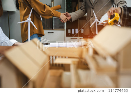 Construction workers, architects and engineers shake hands while working for teamwork and cooperation after completing an agreement in an office facility, successful cooperation concept. Construction workers, architects and engineers shake hands while working for teamwork and cooperation after completing an agreement in an office facility, successful cooperation concept. 114774463