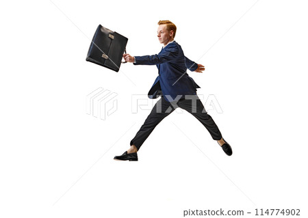 Young businessman, student in formal attire holding bag and running in motion against white studio background. Young businessman, student in formal attire holding bag and running in motion against white studio background. 114774902