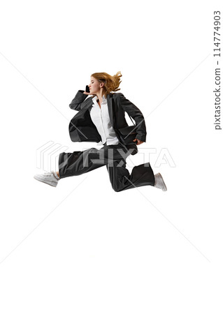 Businesswoman in formal attire having call in mid-air against white studio background. Flexibility and grace in business. 114774903