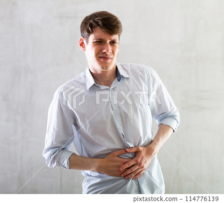Young guy holding on to his sore stomach Young guy holding on to his sore stomach 114776139