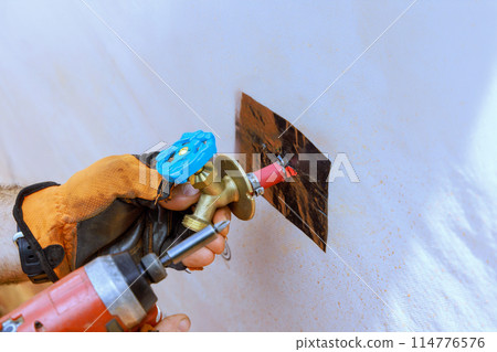Plumber installation external water taps on facade of house 114776576