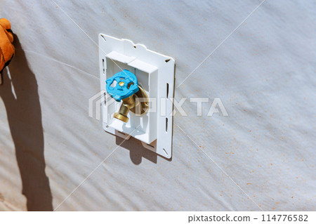 An external water tap is installed on facade of house by plumber 114776582