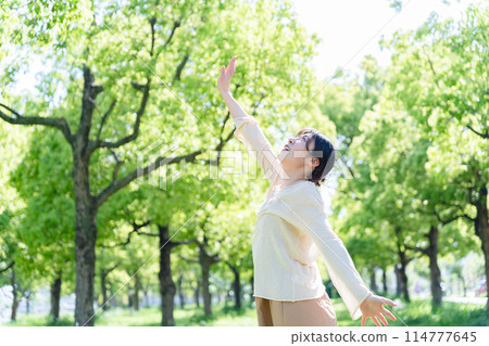 A woman who takes a deep breath at a park 114777645