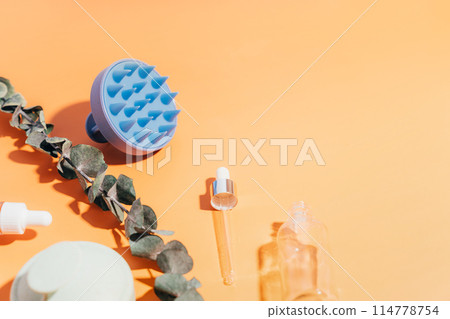 Massagers for scalp and glass jars with serum on a yellow background Massagers for scalp and glass jars with serum on a yellow background 114778754
