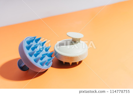 Blue and white massager for scalp on an orange background 114778755