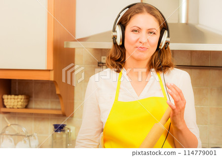 Housewife with earphones in kitchen 114779001