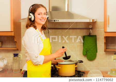 Housewife with earphones in kitchen 114779002