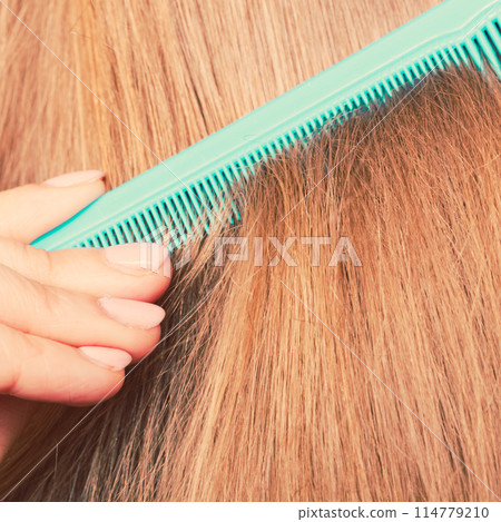 Close up of green comb in red hair. 114779210