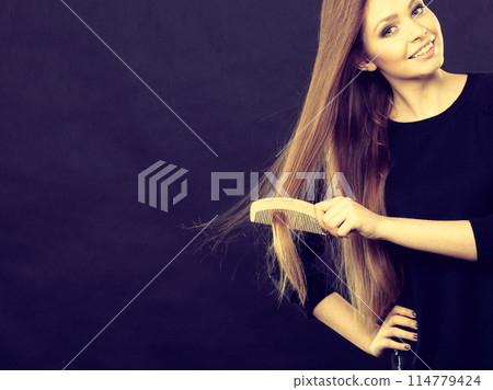 Long haired girl combing her beauty hair. 114779424