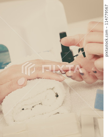 Woman in beauty salon getting manicure done. 114779567