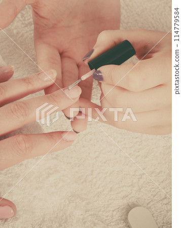 Woman in beauty salon getting manicure done. Woman in beauty salon getting manicure done. 114779584