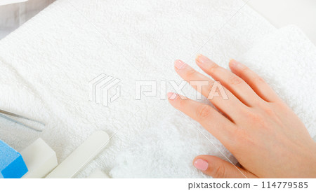 Woman hand on towel, next to manicure set Woman hand on towel, next to manicure set 114779585