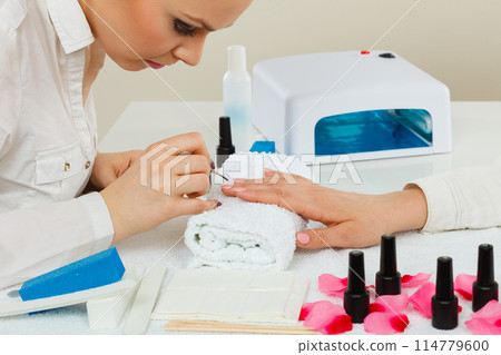 Female beautician making nails. 114779600