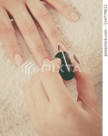 Woman in beauty salon getting manicure done. 114779611