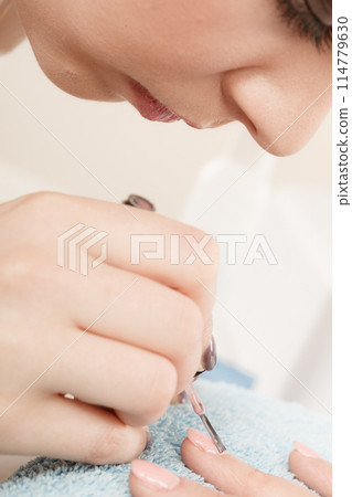 Woman in beauty salon getting manicure done. Woman in beauty salon getting manicure done. 114779630
