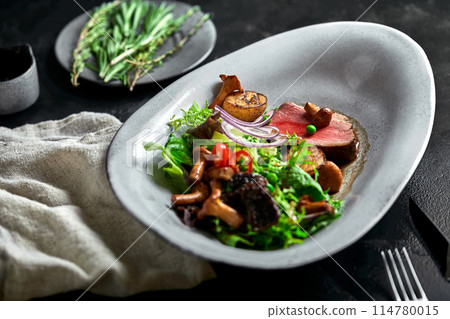 beef tagliata with vegetables. Close-up, low key, gray background. beef tagliata with vegetables. Close-up, low key, gray background. 114780015