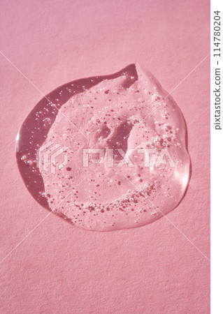 Drop of serum shimmering in the sun on a pink background. 114780204