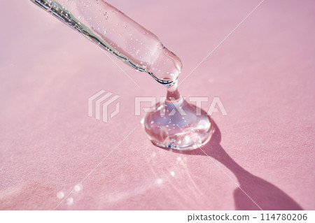 Pipette with serum shimmering in the sun on a pink background. 114780206
