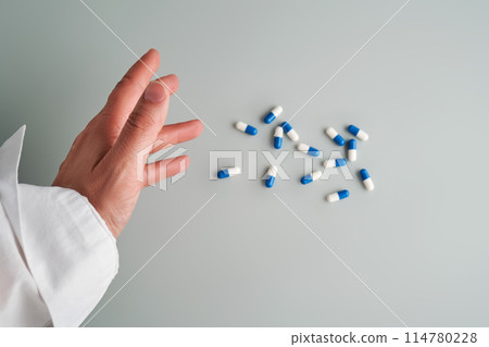 Hand reaches out to a white and blue pill on a blue background. Hand reaches out to a white and blue pill on a blue background. 114780228