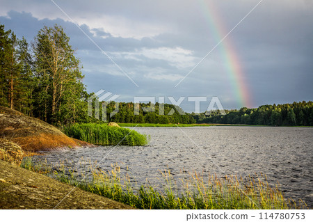 The landscape of Karelia. View of a small stone island surrounded by water, a rainbow after the rain. Gulf of Finland The landscape of Karelia. View of a small stone island surrounded by water, a rainbow after the rain. Gulf of Finland 114780753
