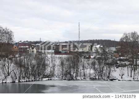 Calm lake scene with snow in early spring. Slope overgrown with trees. Calm lake scene with snow in early spring. Slope overgrown with trees. 114781079