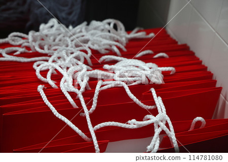 A stack of red paper bags with white rope handles. A stack of red paper bags with white rope handles. 114781080