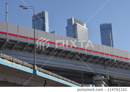 Overpasses on the background of skyscrapers. Blue sky and bright sun. Transport interchanges 114781102