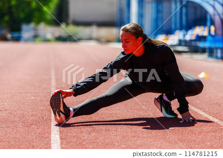 Young fitness sportswoman stretching her legs at the track and field stadium Young fitness sportswoman stretching her legs at the track and field stadium 114781215