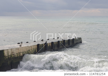Sochi, Russia 05.07.2021. Breakwater pier summer black sea cloudy. Sochi, Russia 05.07.2021. Breakwater pier summer black sea cloudy. 114781254