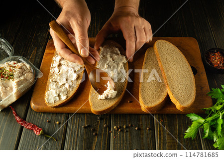 Men hands spread grated lard onto rye bread with a spoon to prepare nourishing and tasty sandwiches. Ukrainian national food 114781685