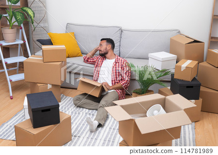 tired young man moving his new home, signifying the transition in the world of relocation, whether renting or buying 114781989