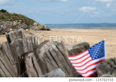Utah Beach WWII with Flag of USA selective focus on beach and ocean. Sandy beach and fence posts. Normandy France rememberance of Veterans Day. High quality photo 114782558