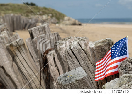 Utah Beach WWII with Flag of USA selective focus on flag. Sandy beach and fence posts. Normandy France rememberance of Veterans Day. High quality photo Utah Beach WWII with Flag of USA selective focus on flag. Sandy beach and fence posts. Normandy France rememberance of Veterans Day. High quality photo 114782560