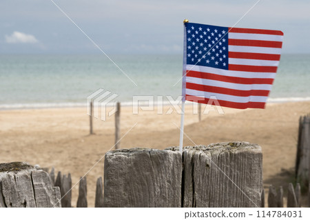 Utah Beach in Normandy, France. Closeup USA flag on wood sea fence. Grass and sand dunes. Sunny sky light ble clouds. High quality photo Utah Beach in Normandy, France. Closeup USA flag on wood sea fence. Grass and sand dunes. Sunny sky light ble clouds. High quality photo 114784031