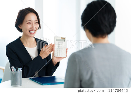 Business woman having a meeting using a calculator 114784443