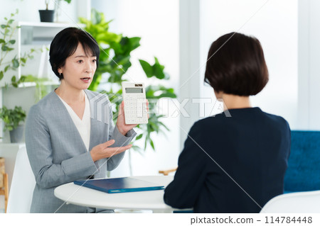 Business woman having a meeting using a calculator Business woman having a meeting using a calculator 114784448