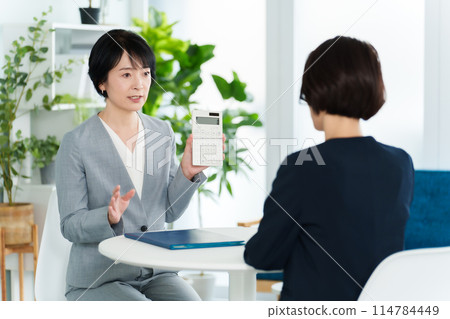 Business woman having a meeting using a calculator Business woman having a meeting using a calculator 114784449