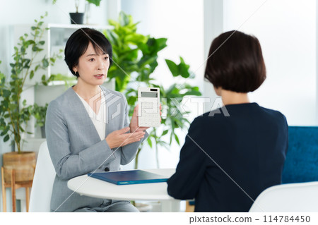 Business woman having a meeting using a calculator 114784450