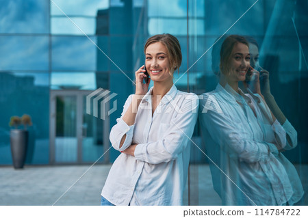 Smiling businesswoman talking on smartphone while 114784722