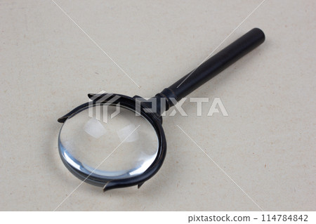 Antique magnifying glass on paper 114784842
