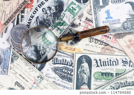 Old US banknotes and silver certificates with silver dollar coins and magnifying glass Old US banknotes and silver certificates with silver dollar coins and magnifying glass 114784880