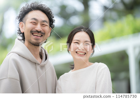 Close-up of a married couple smiling amidst fresh greenery Close-up of a married couple smiling amidst fresh greenery 114785730
