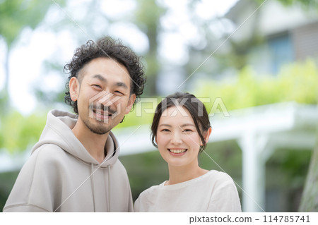 Close-up of a married couple smiling amidst fresh greenery, looking at the camera 114785741