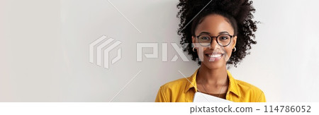 A woman wearing glasses is seated in front of a laptop 114786052