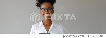 A woman wearing glasses is seated in front of a laptop 114786181