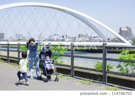 A parent and child walking along the river bank pushing a stroller A parent and child walking along the river bank pushing a stroller 114786703