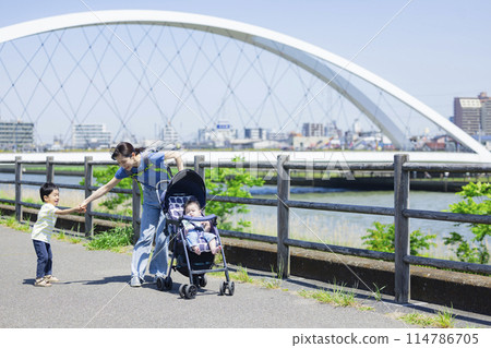 家長和孩子推著嬰兒車沿著河岸行走 家長和孩子推著嬰兒車沿著河岸行走 114786705
