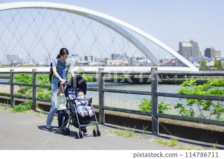 A parent and child walking along the river bank pushing a stroller A parent and child walking along the river bank pushing a stroller 114786711