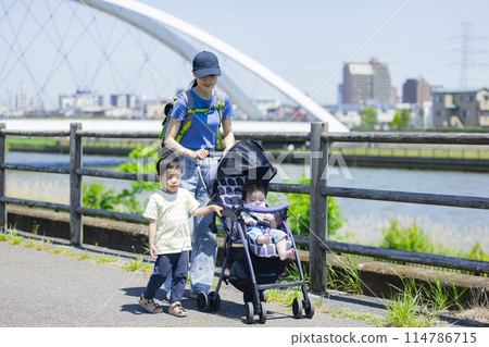 A parent and child walking along the river bank pushing a stroller A parent and child walking along the river bank pushing a stroller 114786715