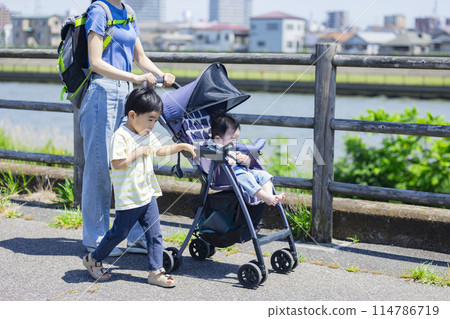 A parent and child walking along the river bank pushing a stroller A parent and child walking along the river bank pushing a stroller 114786719